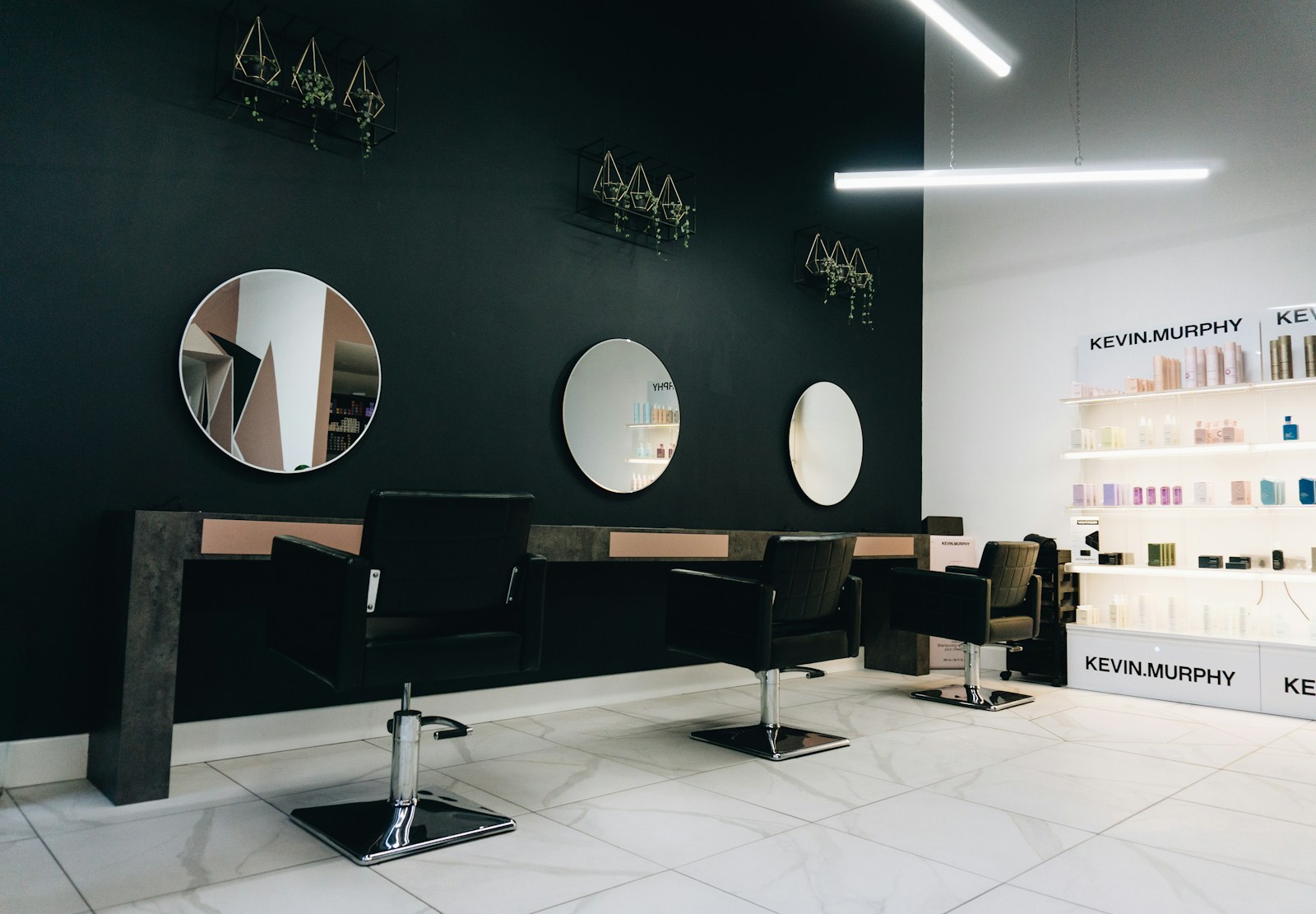 Salon with dark walls, round mirrors and styling chairs