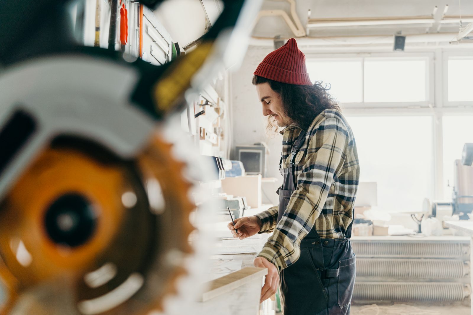 Carpenter measuring wood beside a miter saw